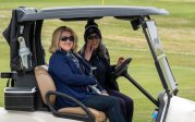 Two women sit in a golf cart.