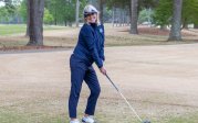 A woman prepares to tee off on a golf course.