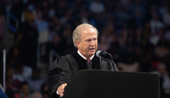 Man speaking behind a podium at a commencement ceremony