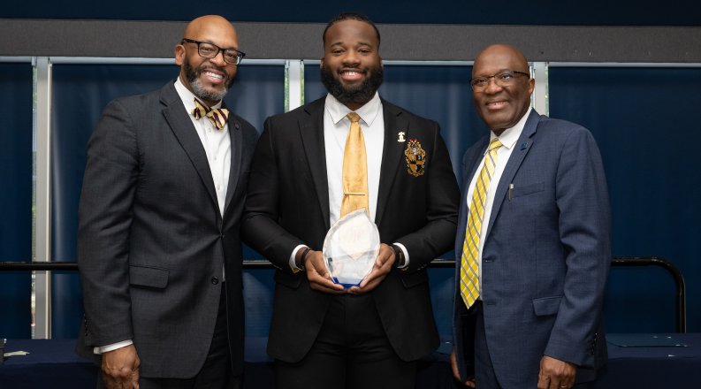 President Hemphill, left, and Provost and Vice President of Academic Affairs Augustine Agho, congratulate Xavier Bervine on winning he 2024 Kaufman Award.