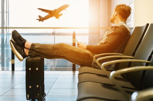 Man sitting in airport watching plane take off out the window