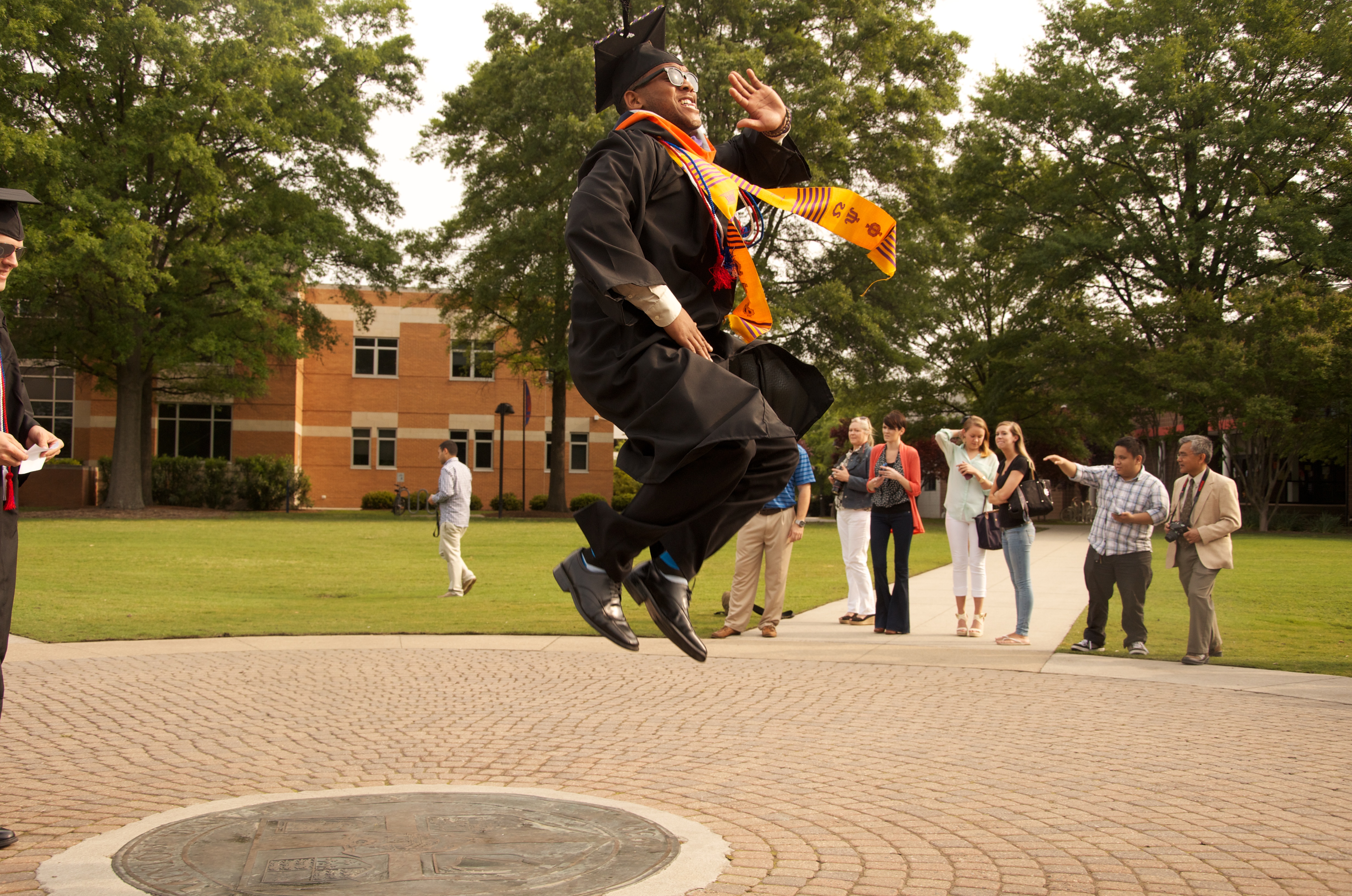 A graduate enthusiastically jumps on the University Seal during the processional at spring commencement 2013
