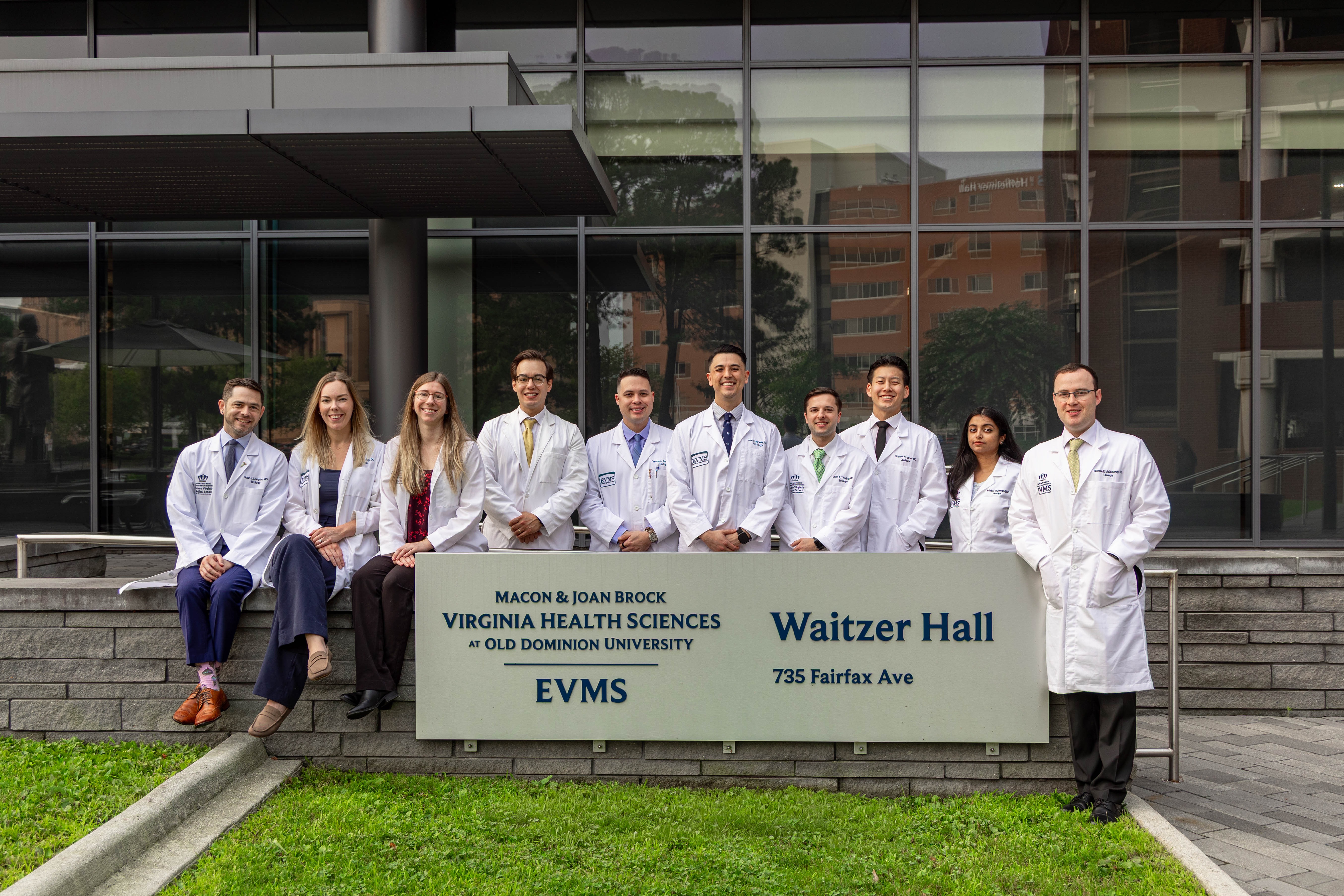 2026 urology residents in white coats pose in front of Waitzer Hall