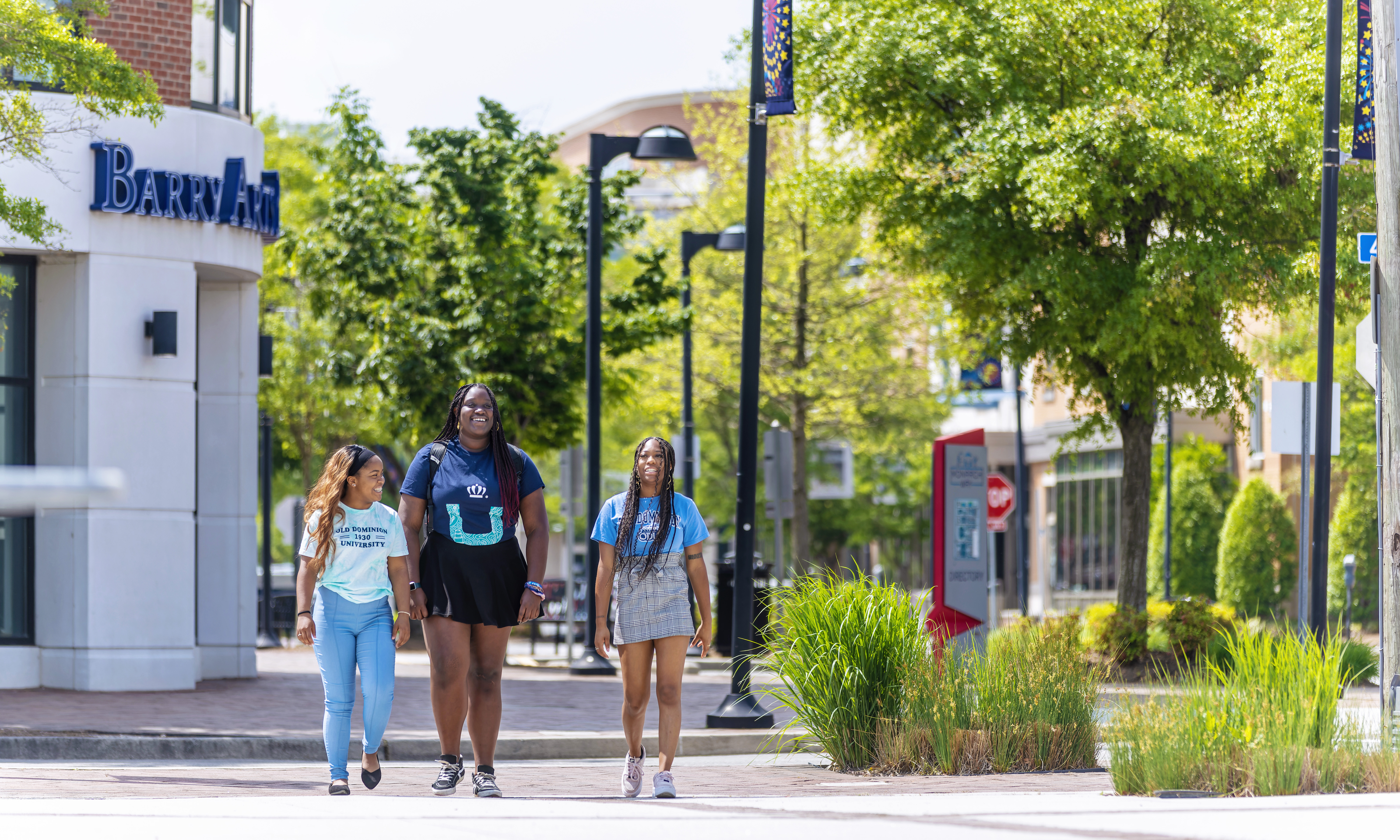three female students wearing odu apparel are walking on monarch way