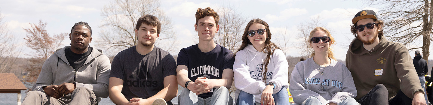 Engineering students pose for photo while sitting on bridge railing.