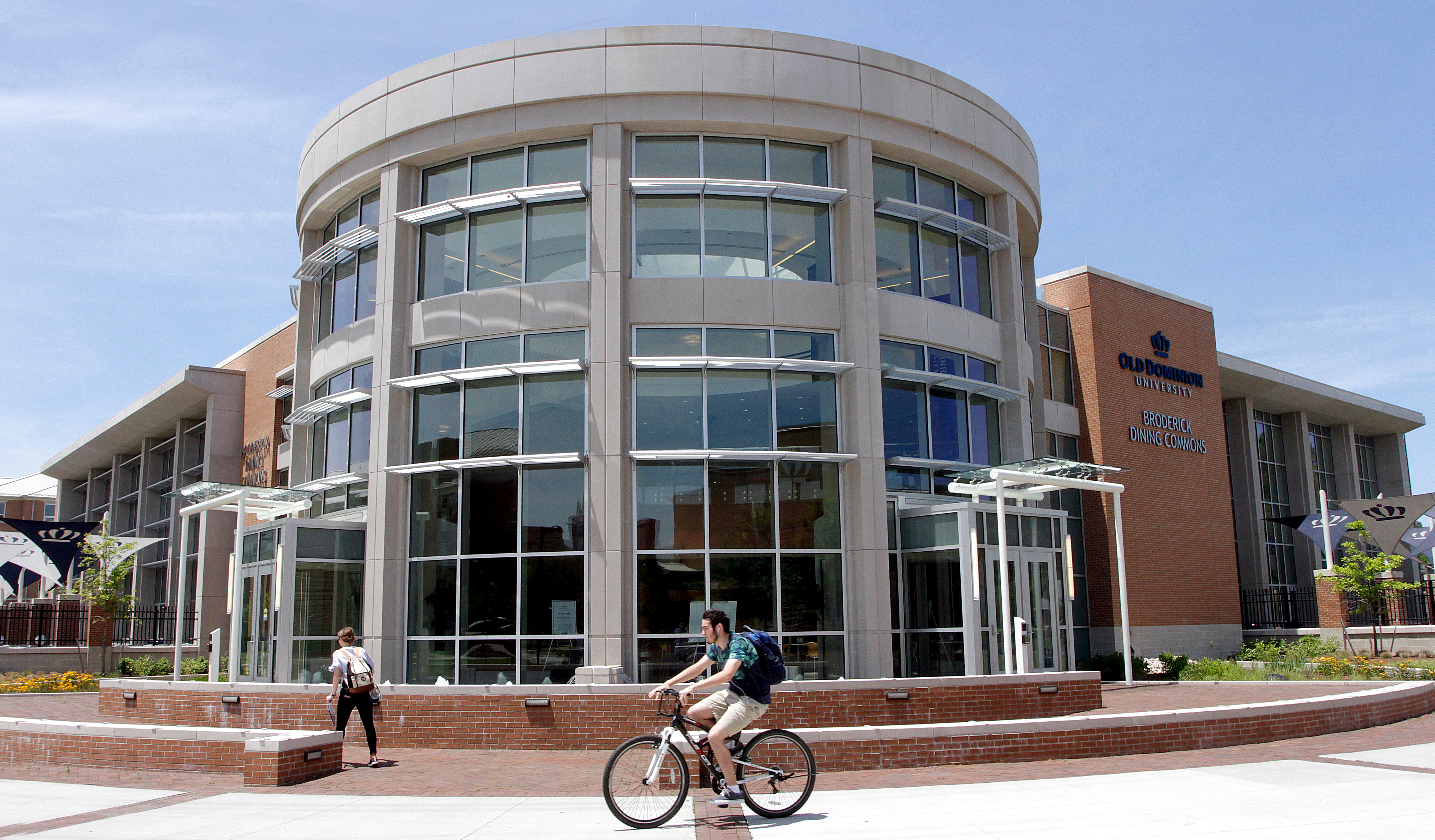 Student riding a bike in front of Broderick Dining Commons