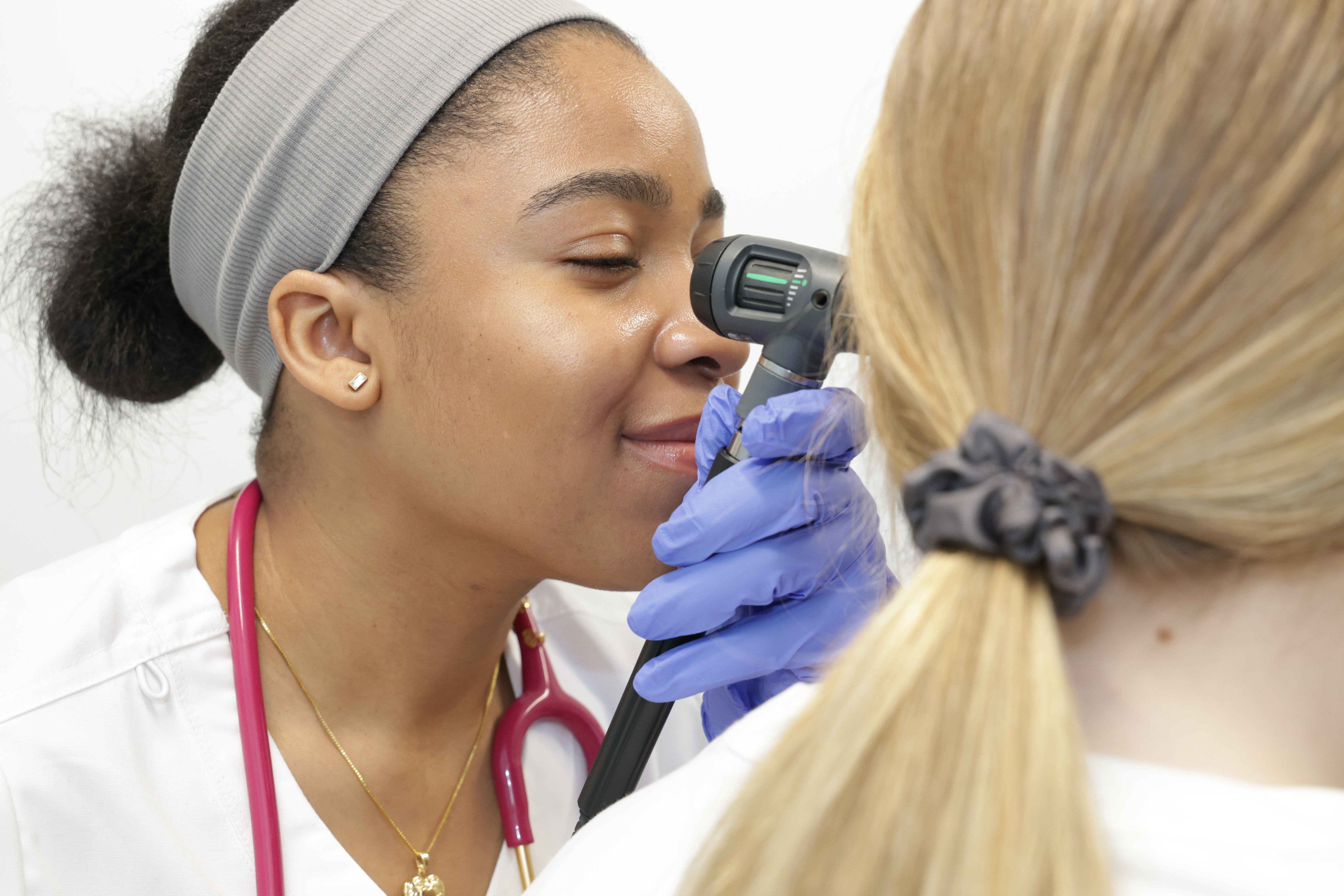 Nursing student uses instrument to look into patient's ear.