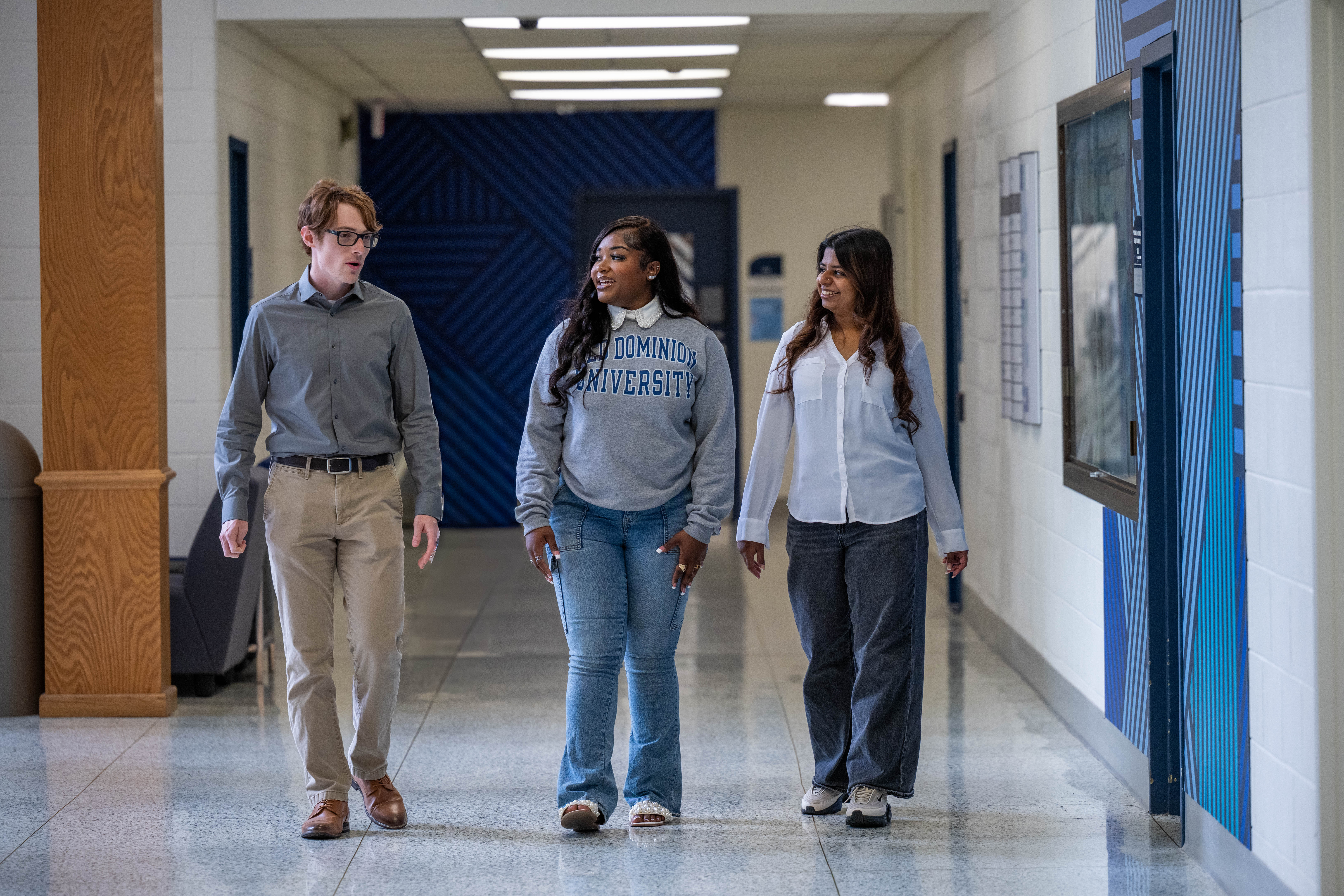 Three Honors College students walk down hallway.