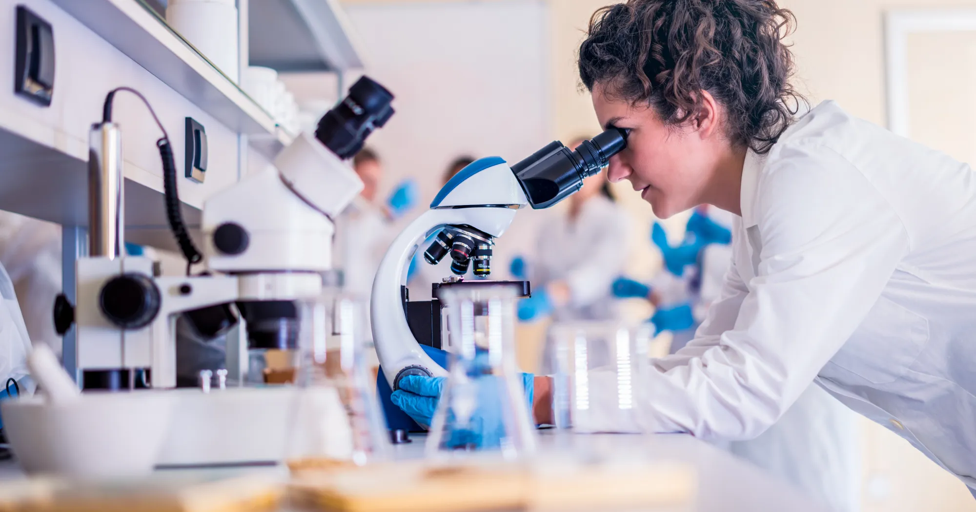 A student looking into a microscope in a lab