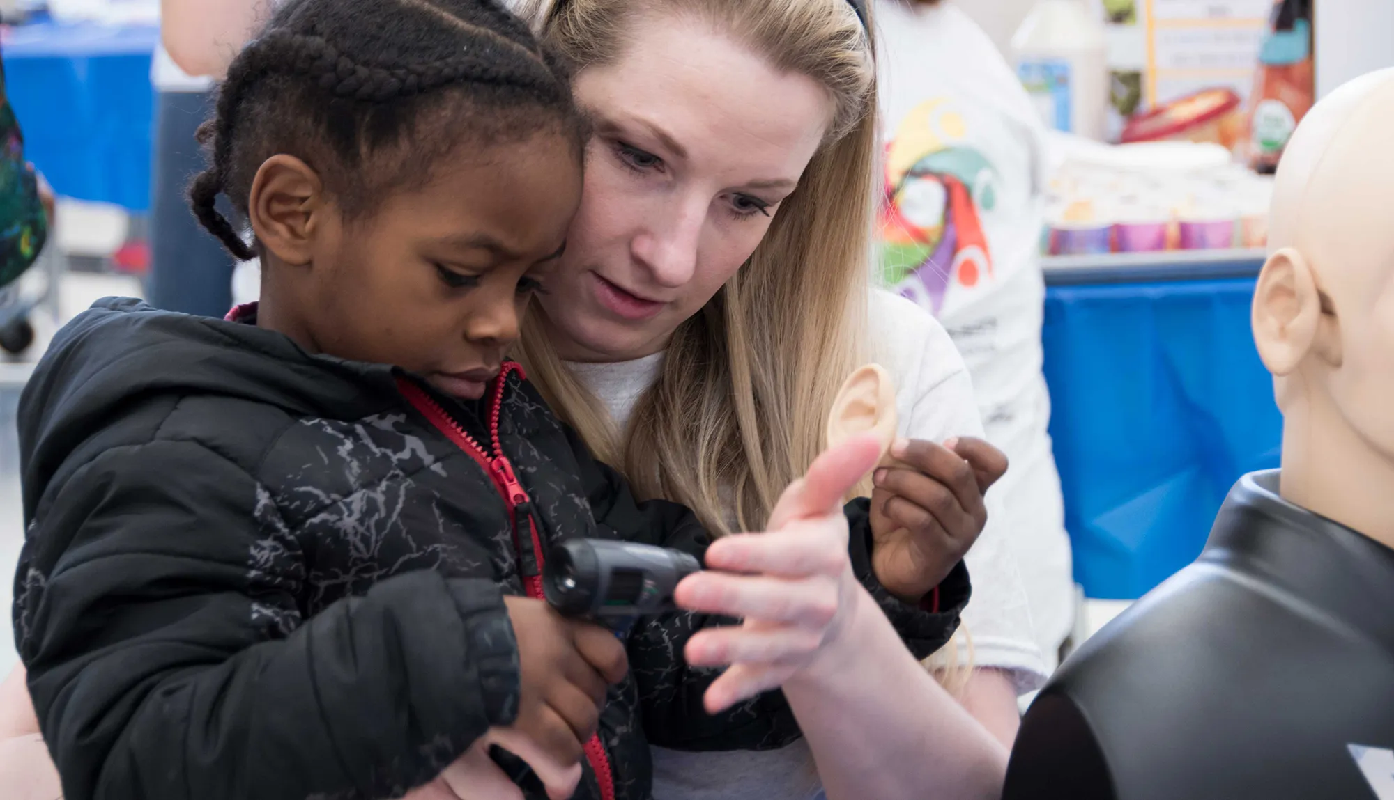 Student showing a child a model of an ear