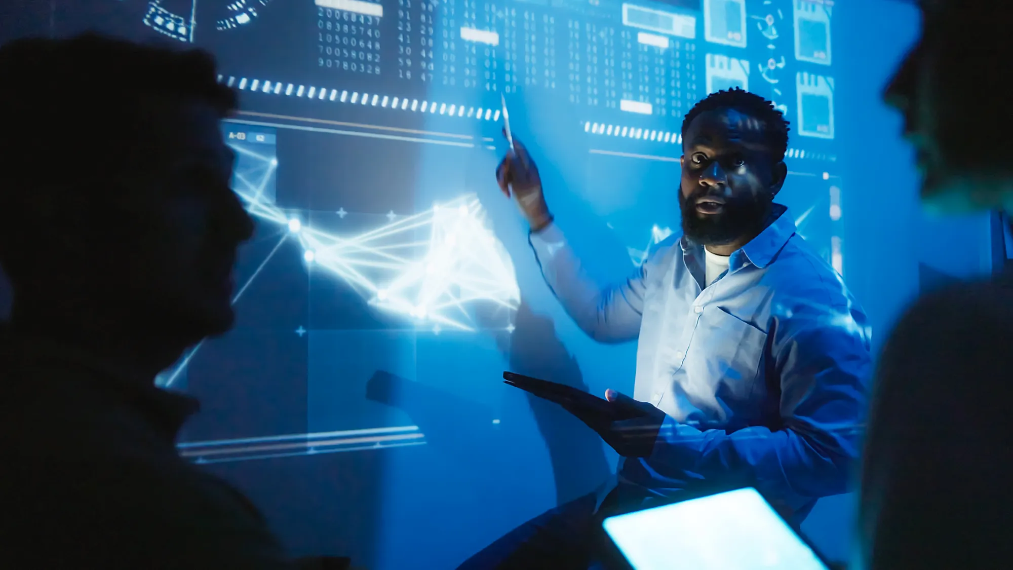 Man in front of projected chart explaining to other scientis