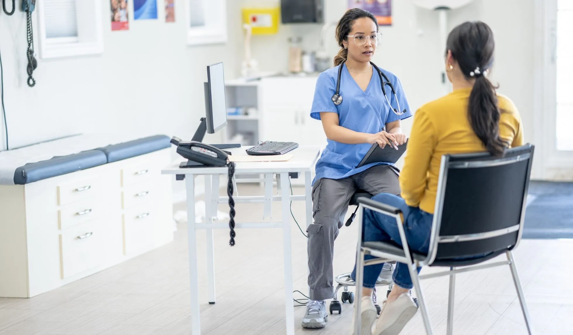 Female doctor talks with patient in exam room
