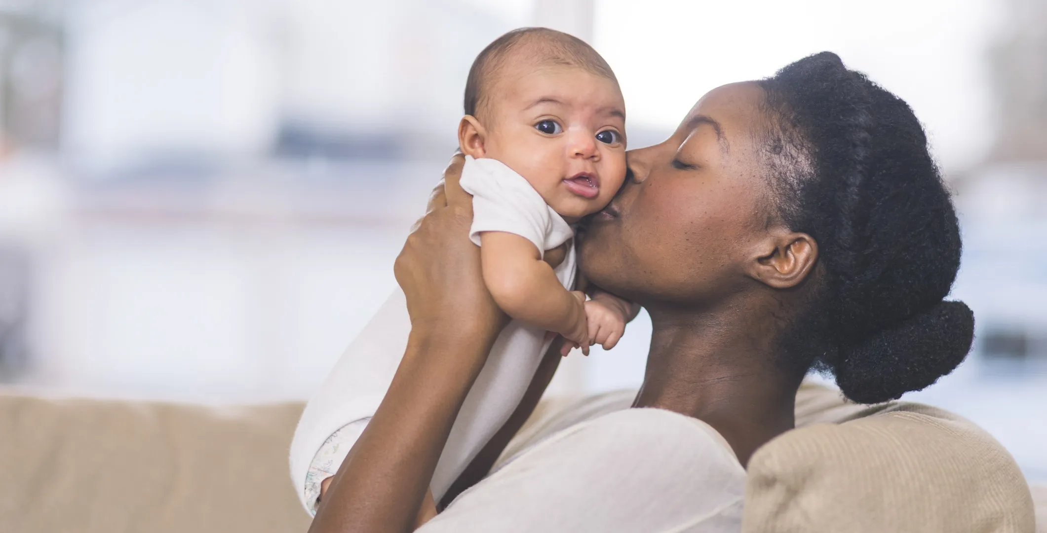 Profile shot of mom holding up newborn to kiss