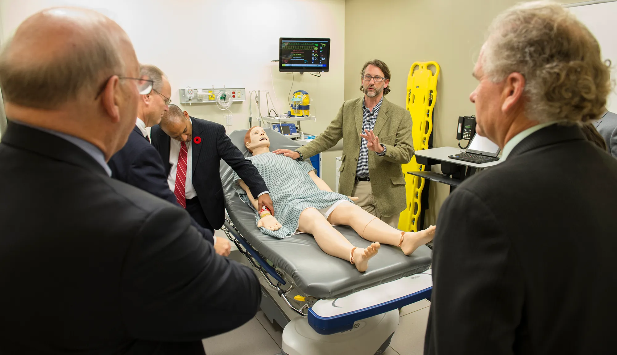 Faculty and staff surround a training manikin in the Sentara