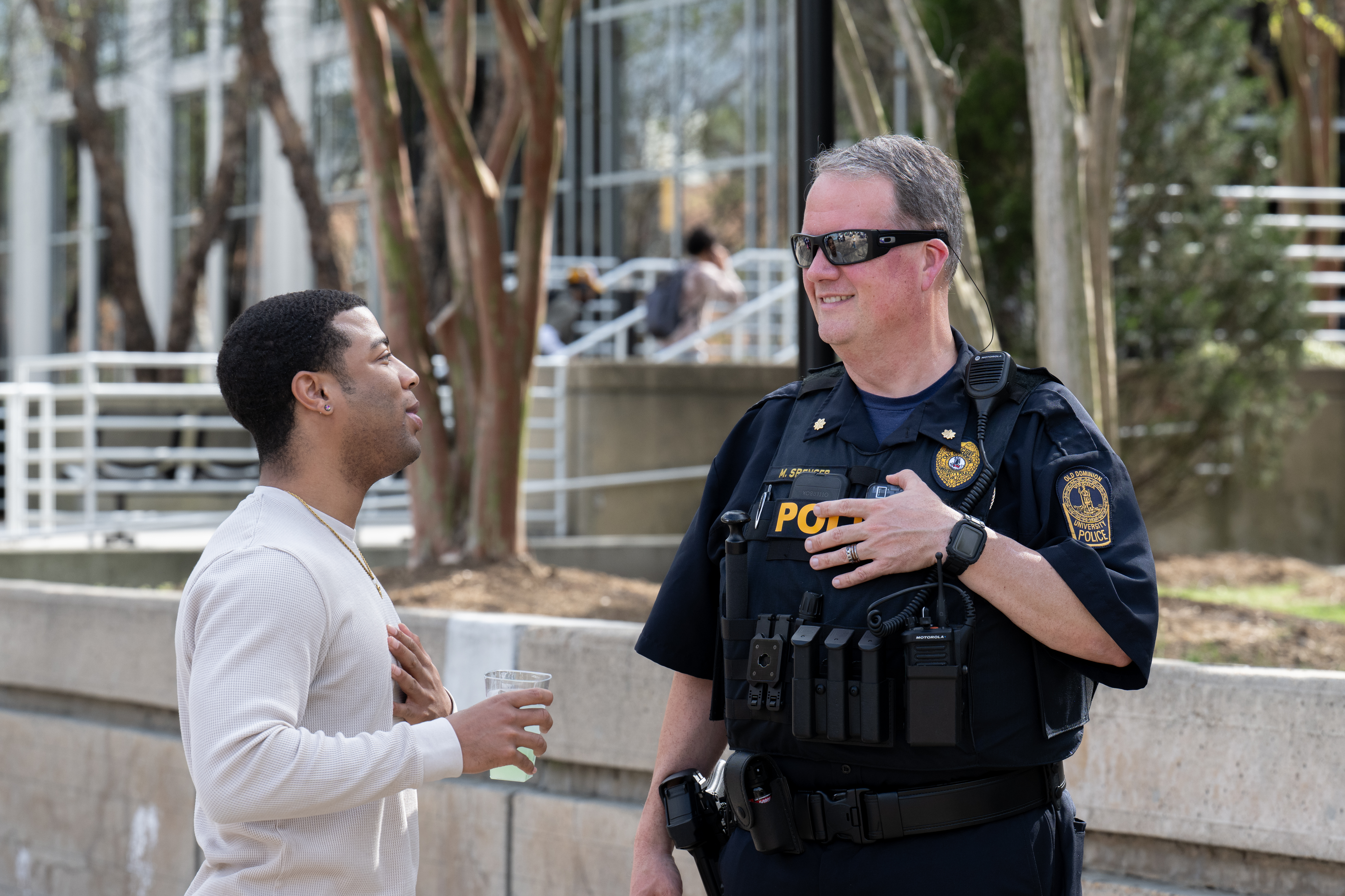 Man holding cup speaks with ODU police officer.