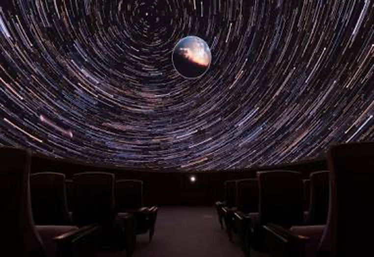 Inside a dark ODU planetarium theater, the earth is shown surrounded by a swirling galaxy.