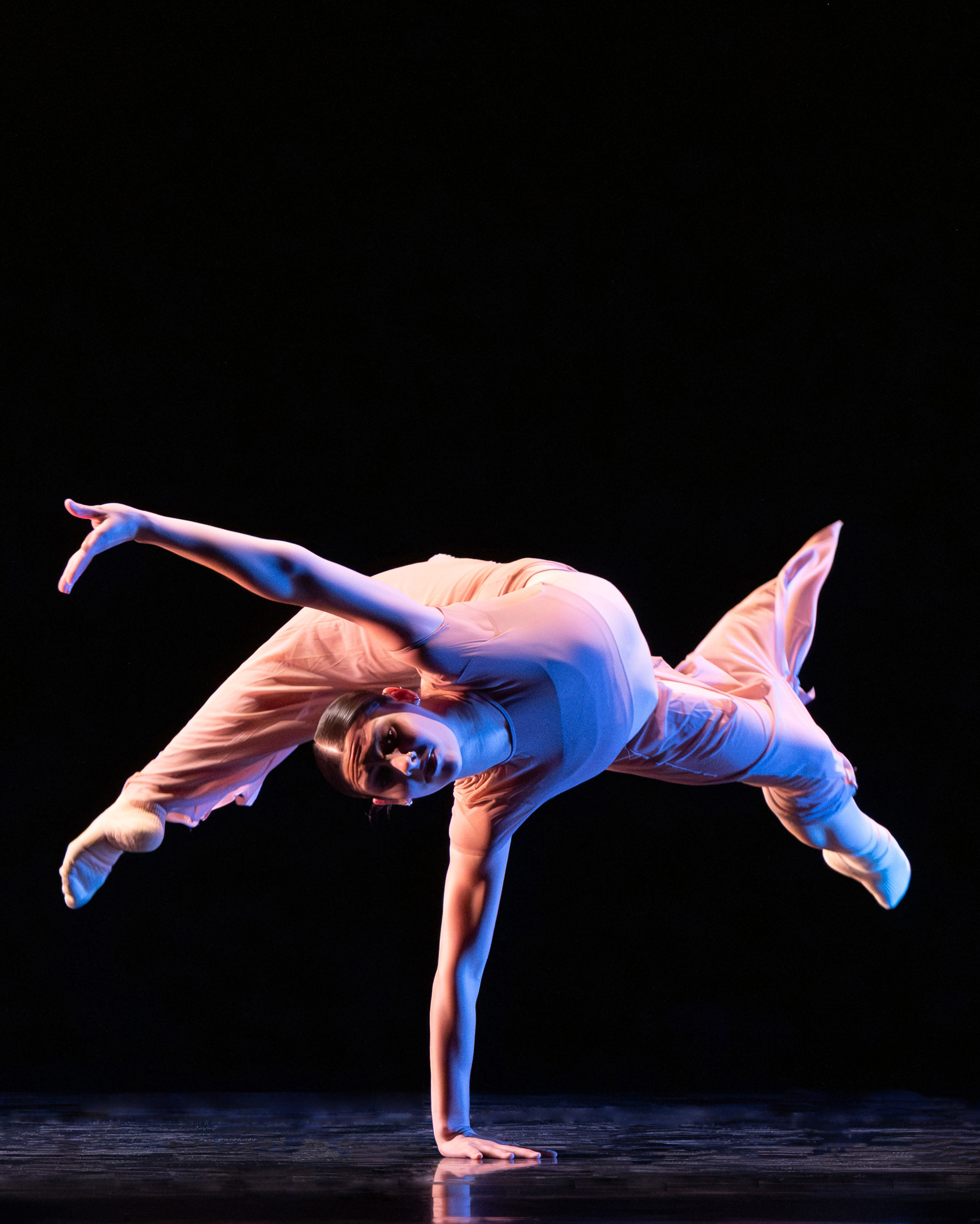 Dancer balances on one hand.