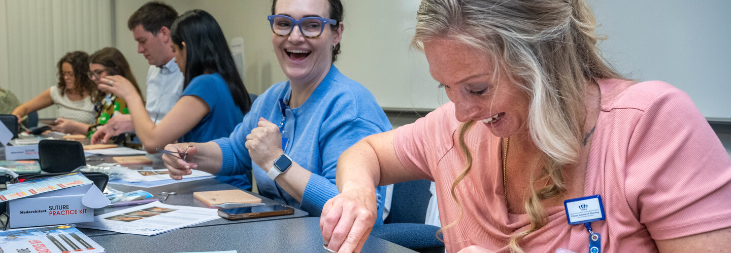 Nursing students sit at table while practicing with sutures.