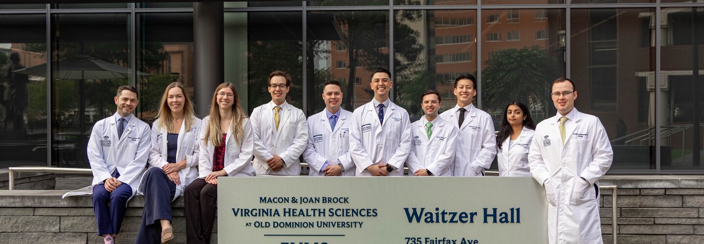 2026 urology residents in white coats pose in front of Waitzer Hall