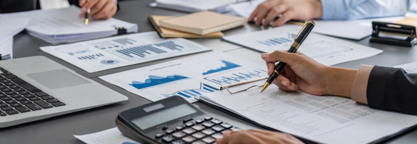 Auditor and accountant review business documents on office table.