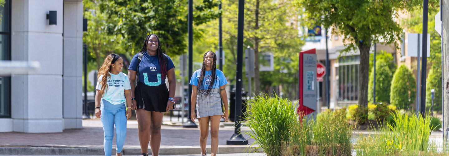 three female students wearing odu apparel are walking on monarch way
