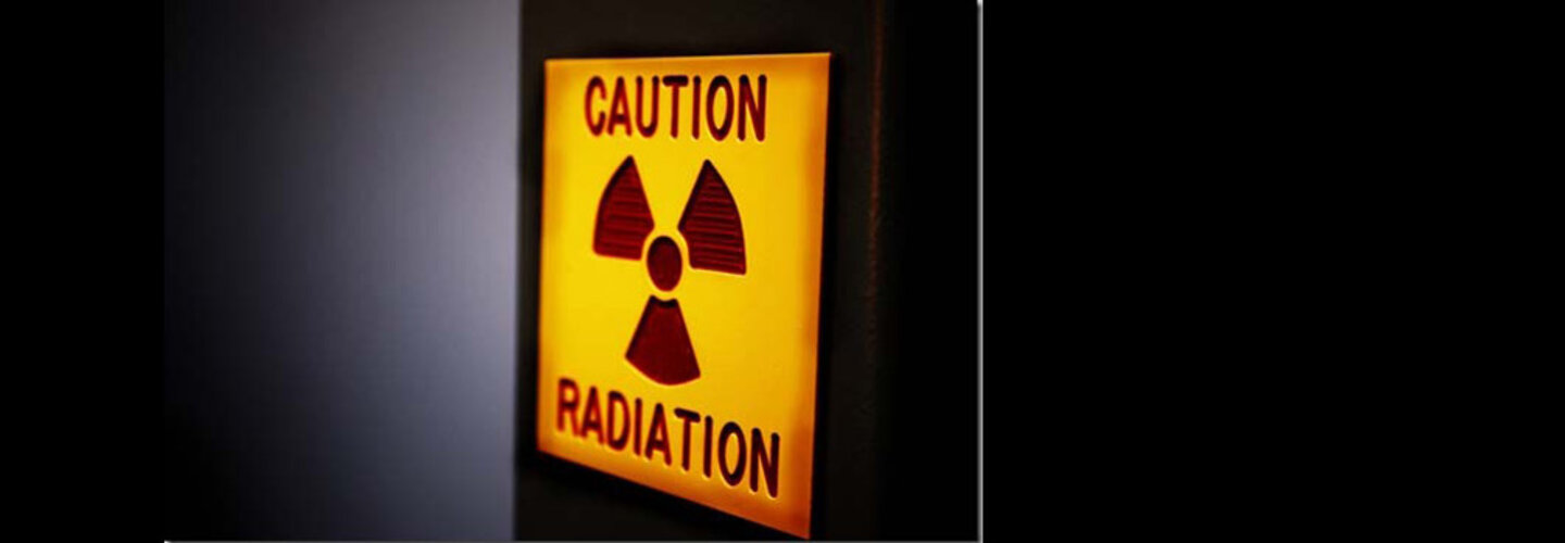 Illuminated sign reads "Caution Radiation"