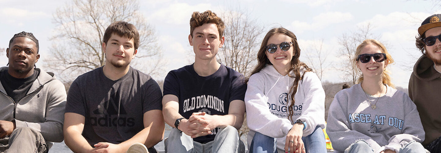Engineering students pose for photo while sitting on bridge railing.