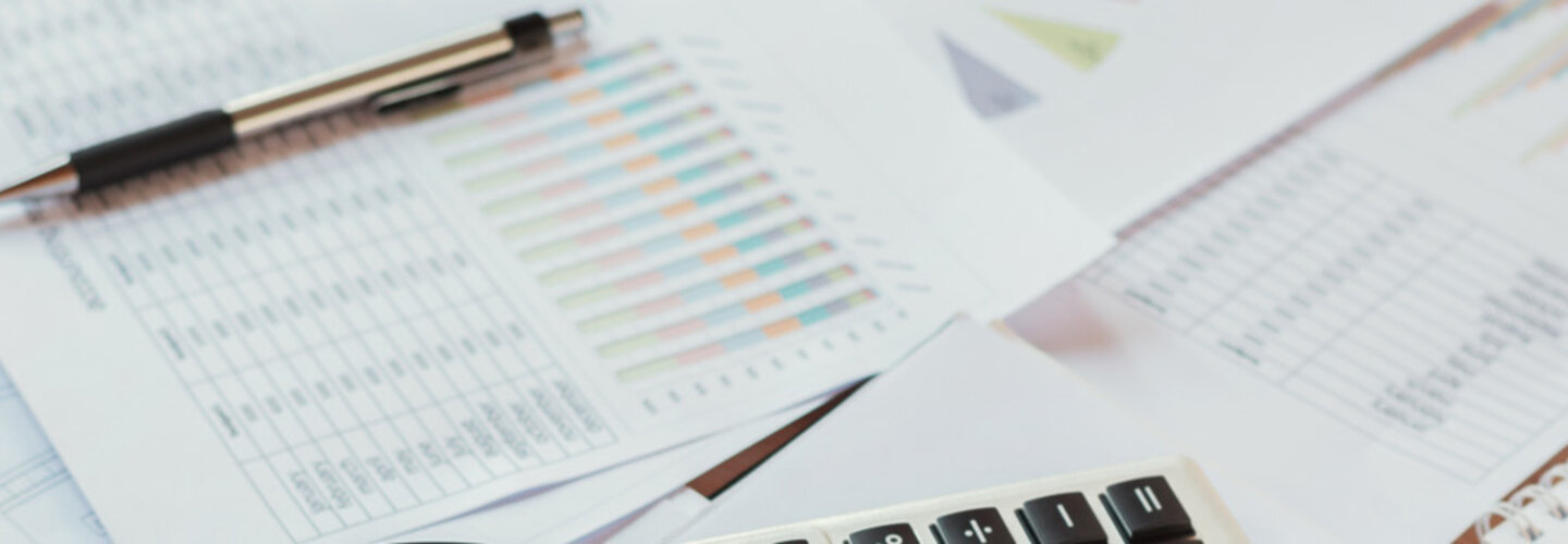 Accounting report, calculator and pen on desk.