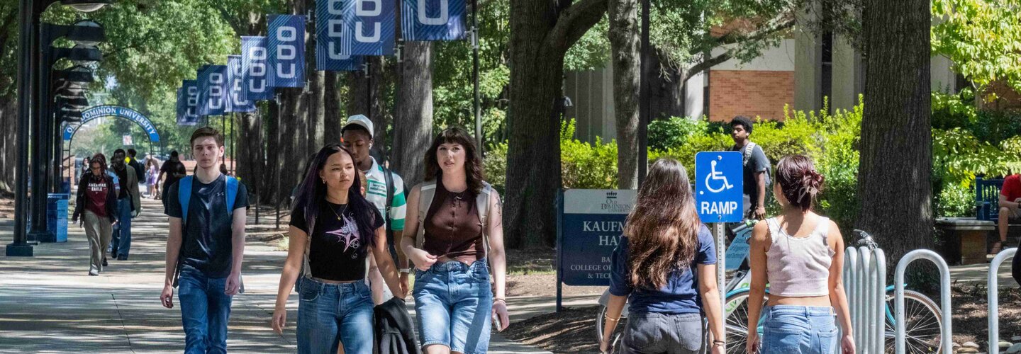 Students walking across campus with ODU flags hanging on posts.