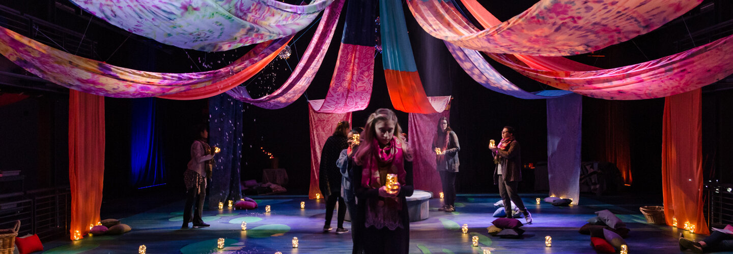 A moody banner image featuring lighting and drapes of a theatre stage.