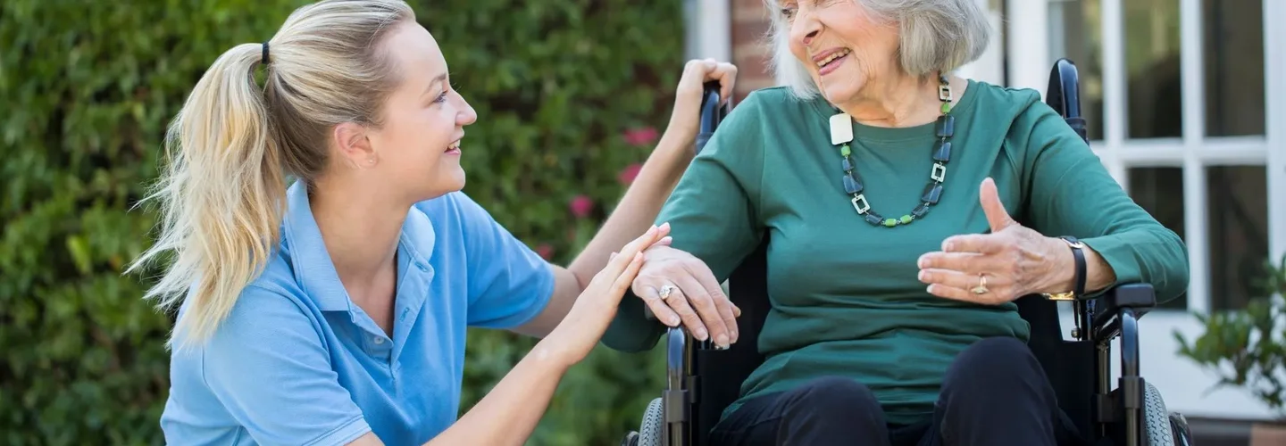 Nurse crouching by lady in wheelchair