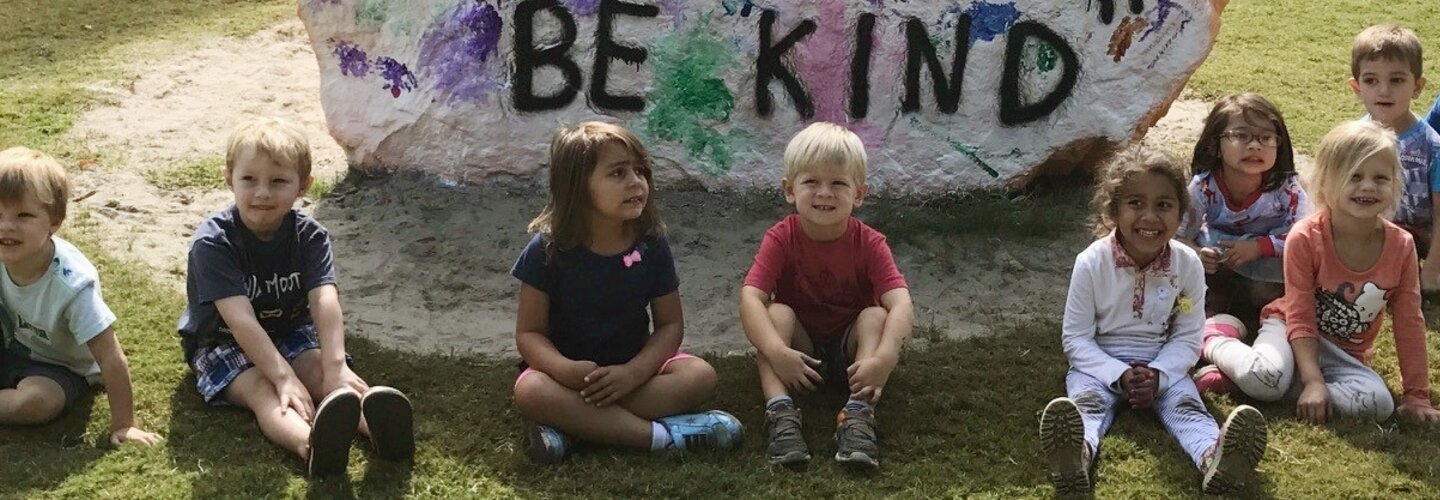 Preschool class from the Children's Learning and Research Center sitting in front of the rock they painted with the words Be Kind