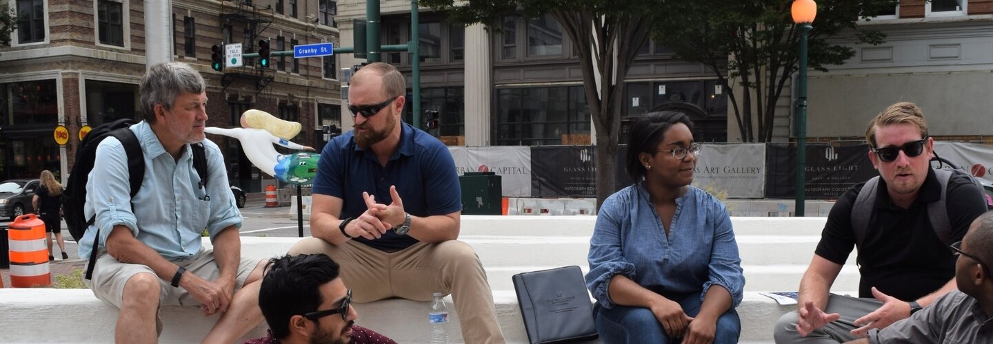 A diverse group of people sitting on steps in a downtown area. 