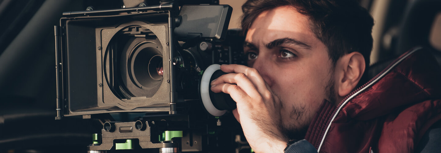 Student looks through film camera. 