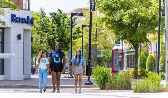 three female students wearing odu apparel are walking on monarch way