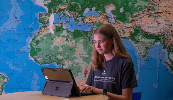 Student on a laptop with a world map behind them