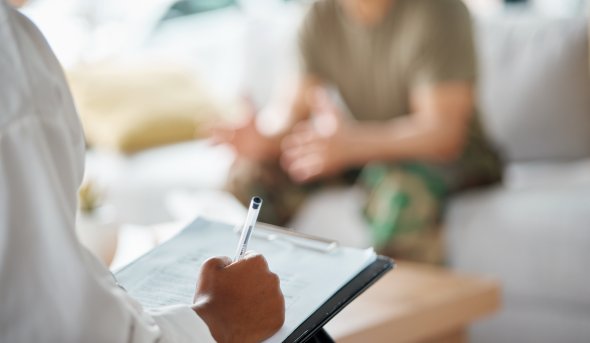 Counselor taking notes on a clipboard with a service member. 