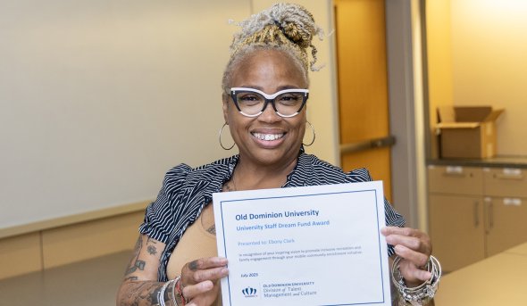 Ebony Clark poses with a certificate showing she is the 2025 Staff Dream Fund award recipient.