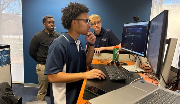 Three people at a computer