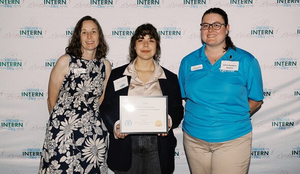 3 students standing middle one holds award