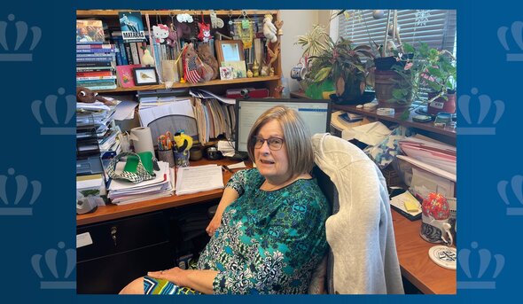 Fran Hassencahl, Ph.D., is shown seated in her Batten Arts and Letters Building office, surrounded by scholarly books, thriving plants and colorful toys.