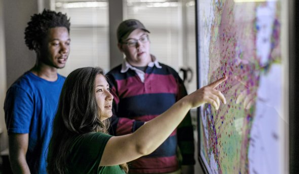 3maritime students work in front of map