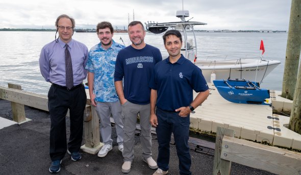 Four men stand in front of boat