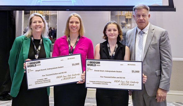four people smiling, two holding big checks