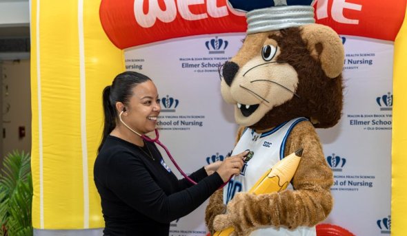 A woman uses a stethoscope to check the heartbeat of the ODU mascot
