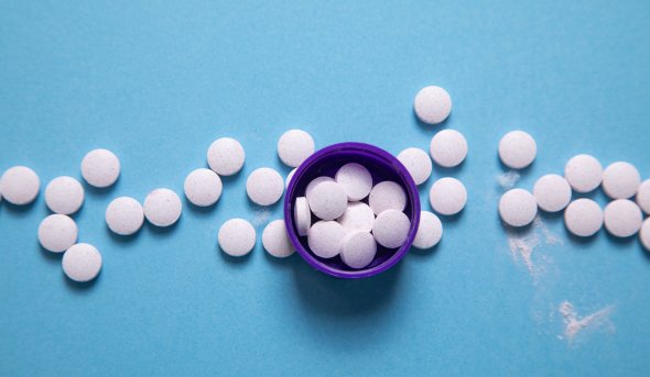 Overhead view of medical pills, both in an open bottle and spread around it.