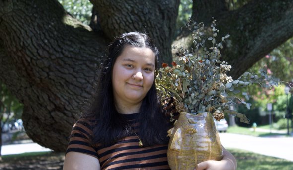 A photo of Kaitlyn Compton with one of her artwork pieces.