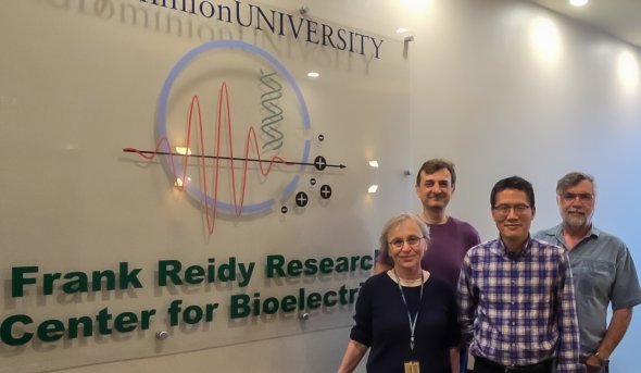 Four faculty members smile for group photo in front of Frank Reidy Research Center for Bioelectrics sign.