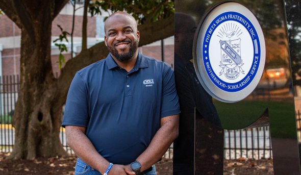 ODU alumnus Occasio Gee next to a fraternity monument. 