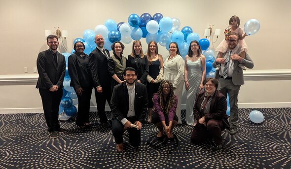 Students in stand in front of a baloon arch